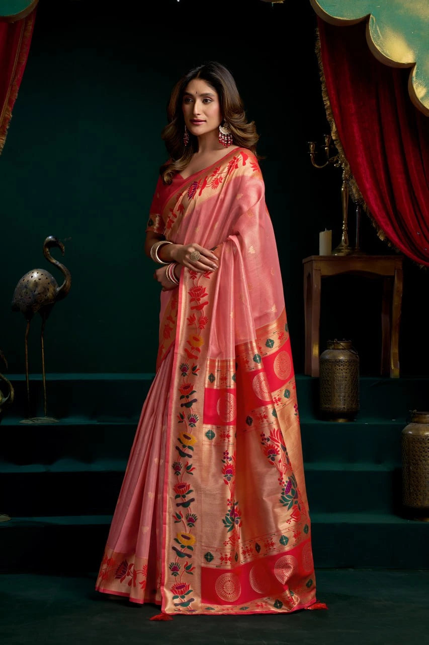 Woman wearing a pink saree with floral patterns in a dark setting